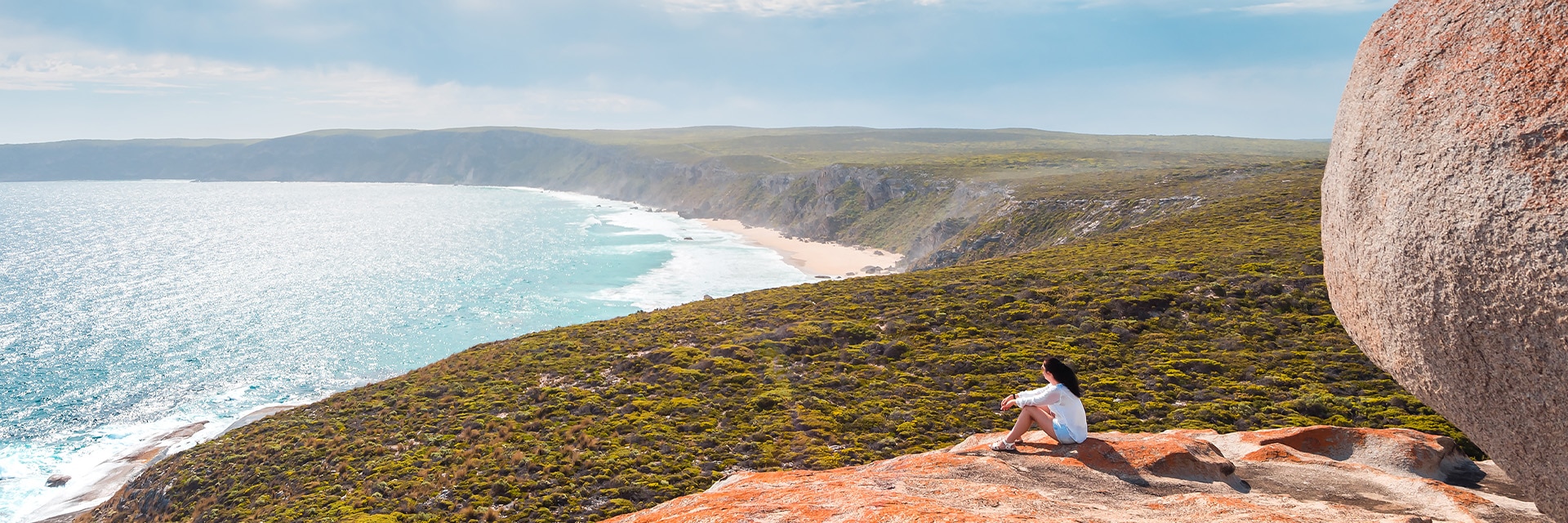 a woman sits on a large rock located in kangaroo island