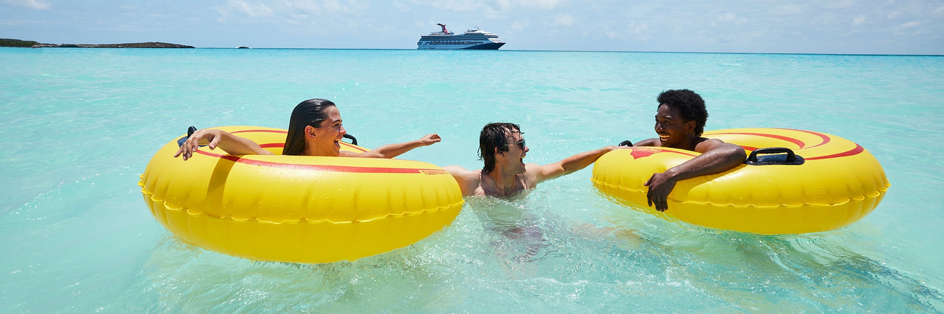 guests using floating tubes in the ocean with a carnival cruise ship in the background