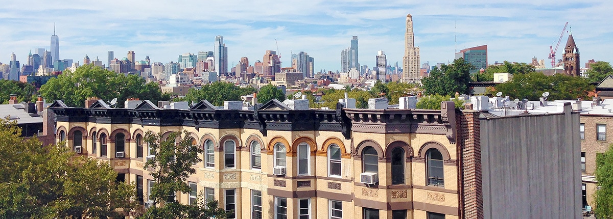 yellow brooklyn brownstones with the new york skyline