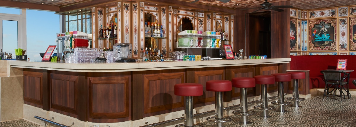 poolside bar with red swivel chairs and art pieces displayed on the walls