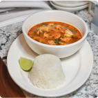 a bowl of soup and rice is served on a dish